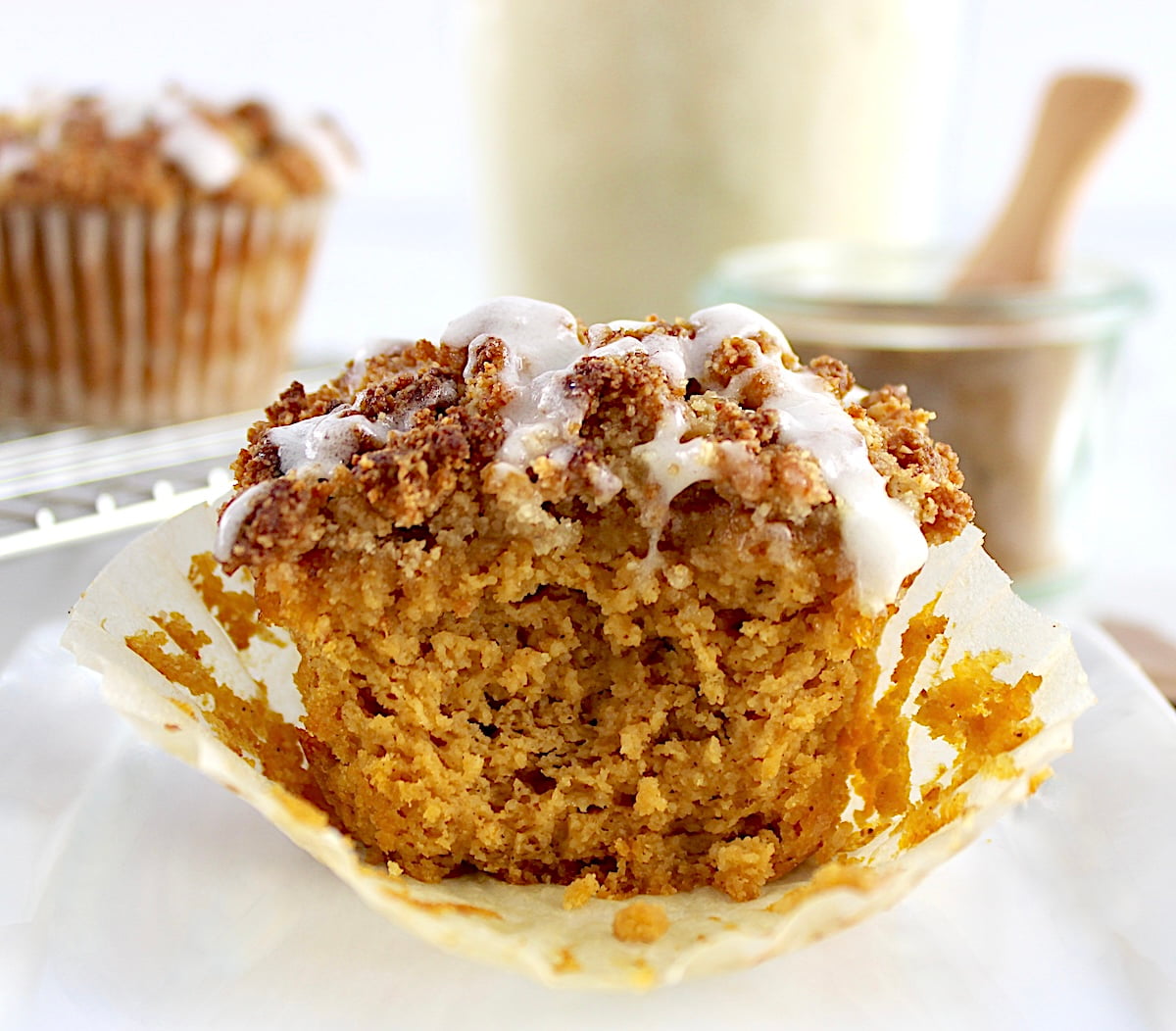 closeup of Keto Pumpkin Coffee Cake Muffin on white plate with bite missing