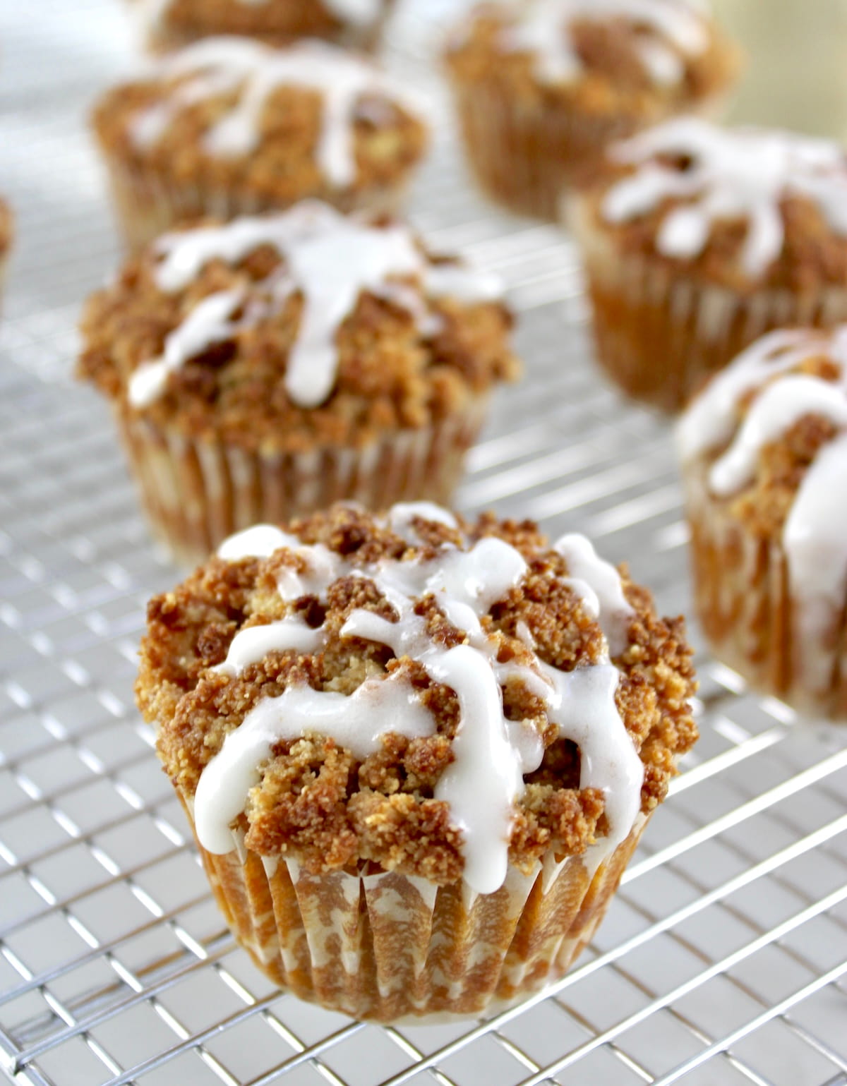 Keto Pumpkin Coffee Cake Muffins on cooling rack with icing dripping