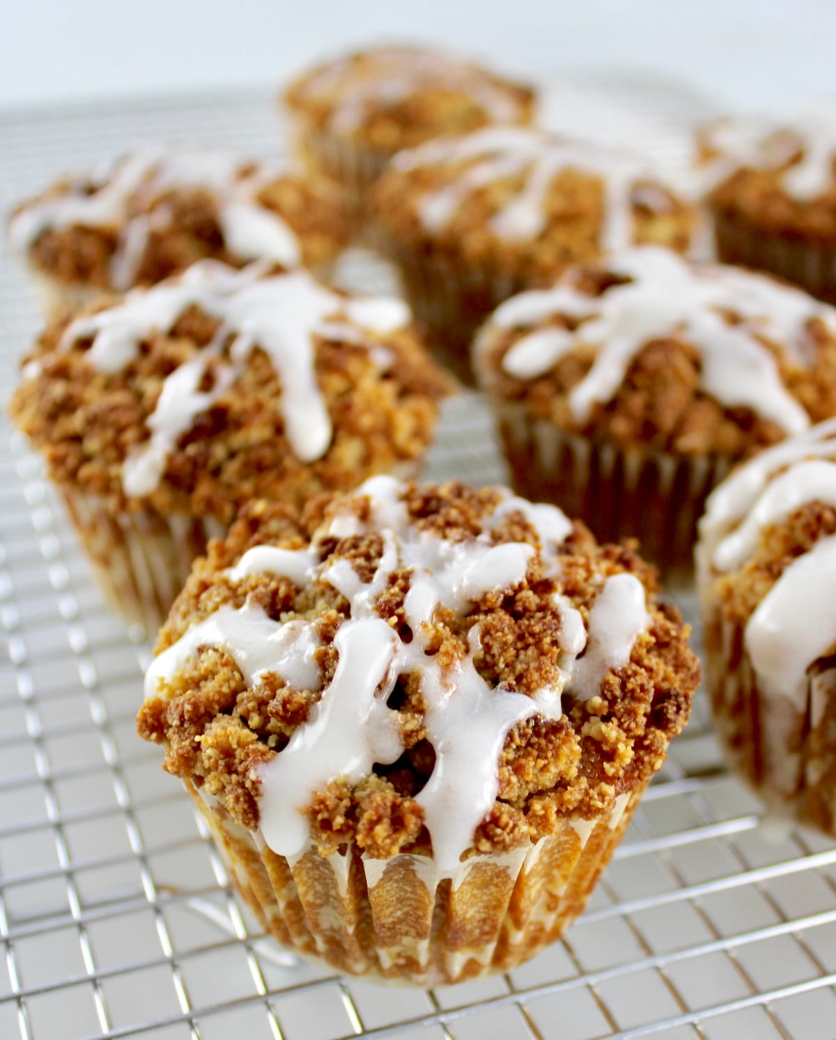 Keto Pumpkin Coffee Cake Muffins on cooling rack with icing dripping
