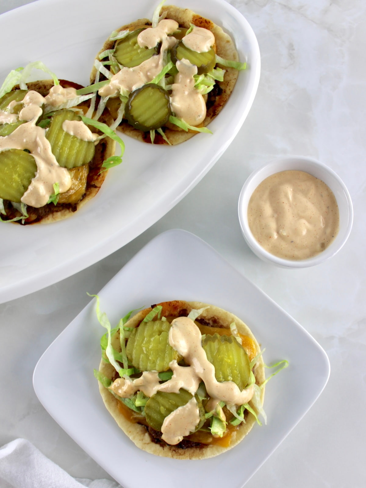 overhead view of Keto Smash Burger Taco on white square plate with more in back
