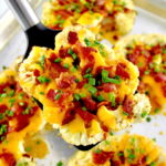 spatula holding up Loaded Cauliflower Steak over baking sheet