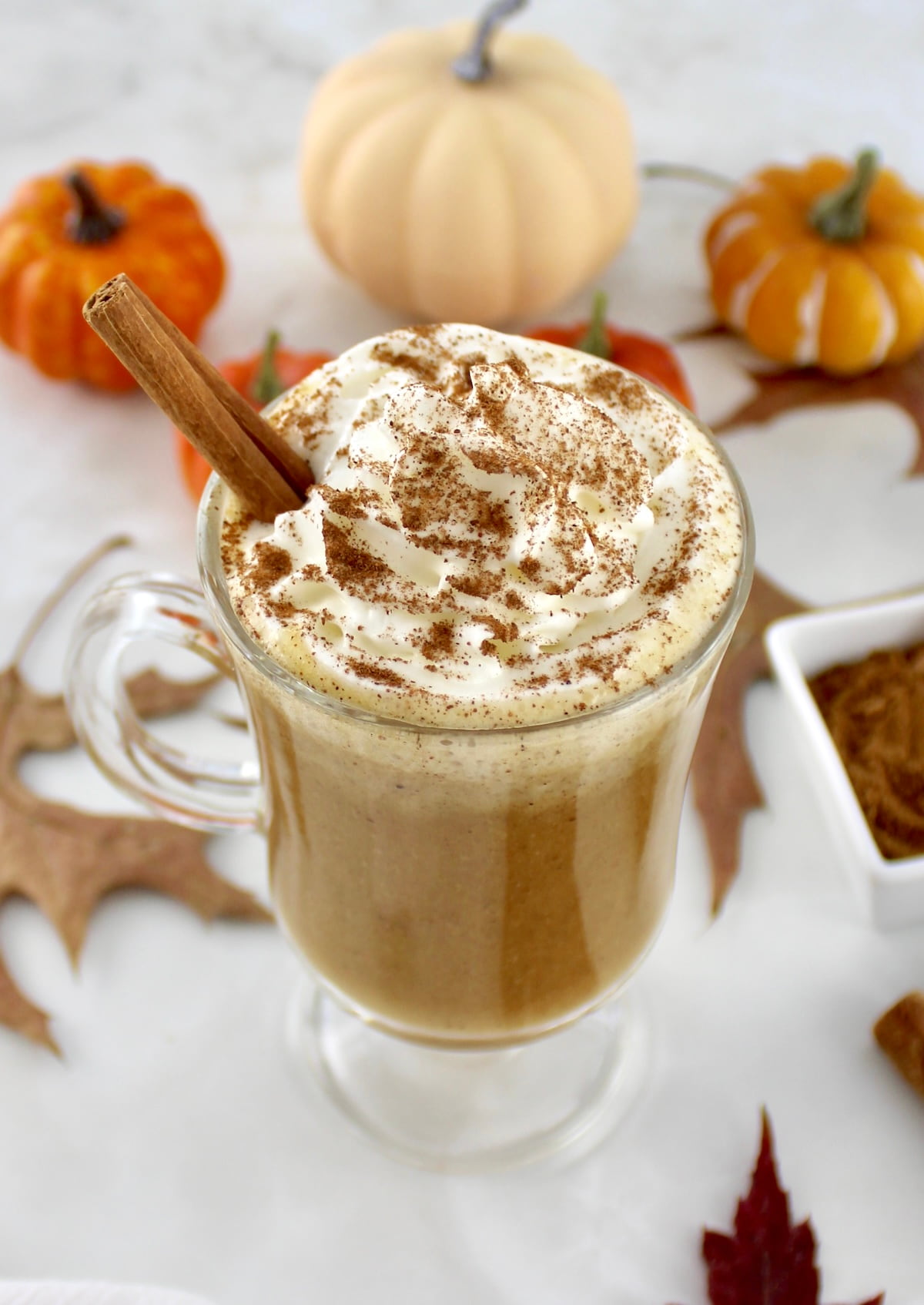 overhead view of Pumpkin Spiced Bulletproof Coffee in glass with whip cream on top and cinnamon stick