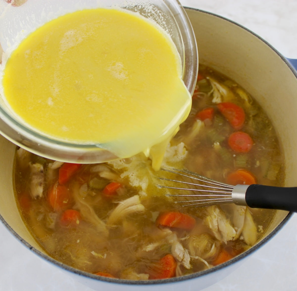 Avgolemono Soup with lemon and eggs being whisked into the pot