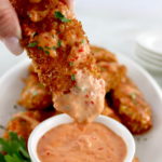 dipping Bang Bang Chicken Tender into sauce in white cup