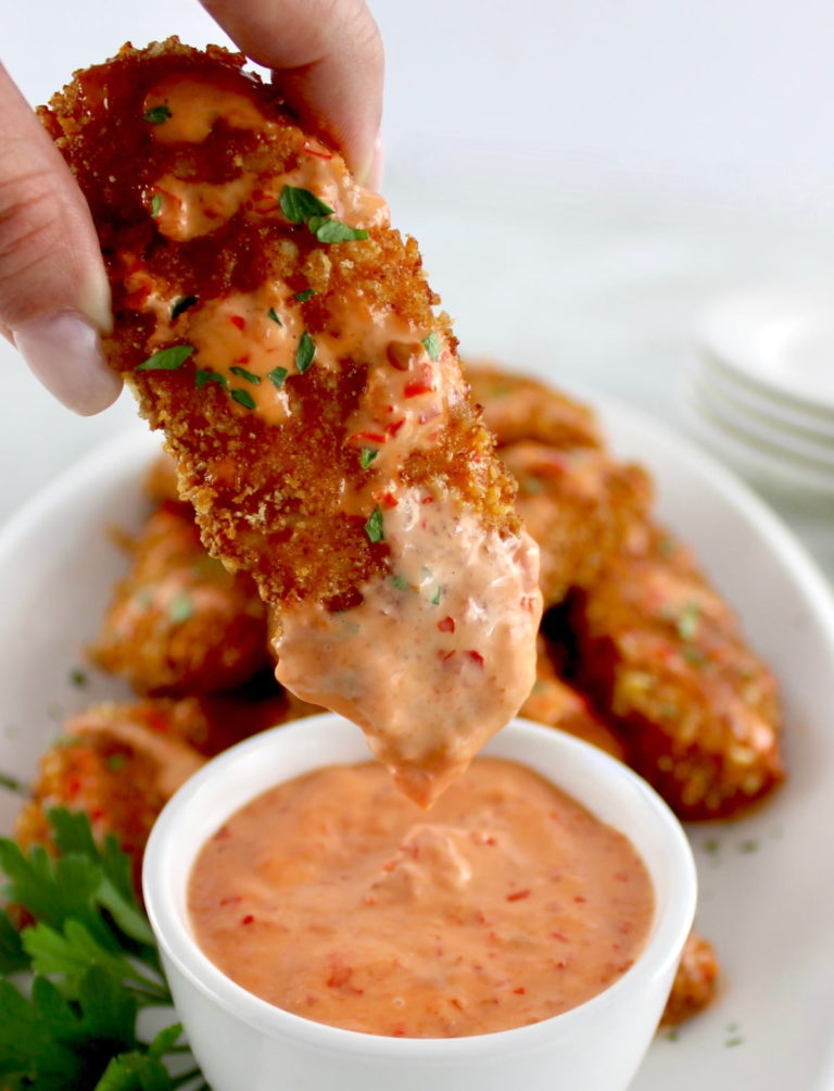 dipping Bang Bang Chicken Tender into sauce in white cup