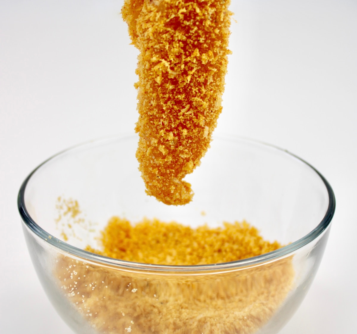 dipping chicken tender into keto breading in glass bowl