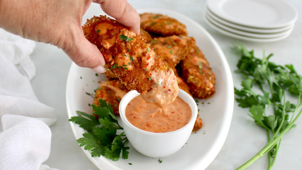 holding Bang Bang Chicken Tender dipped in sauce