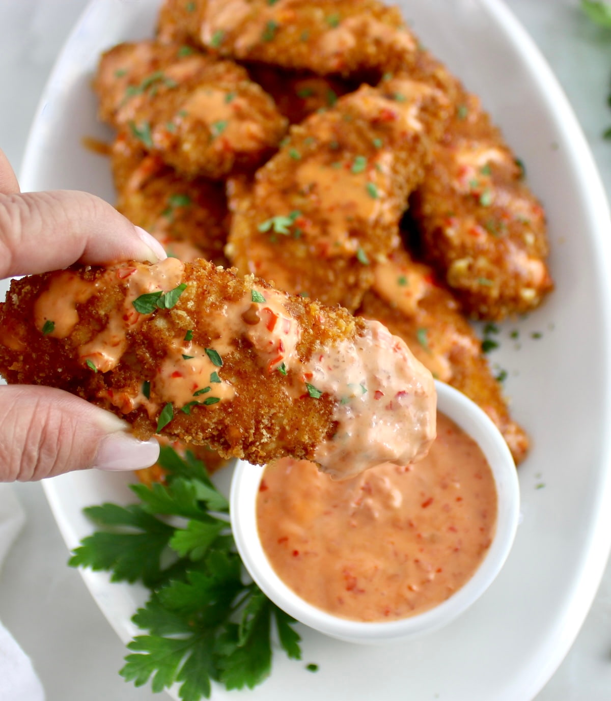 closeup of holding up Bang Bang Chicken Tender dipped in sauce