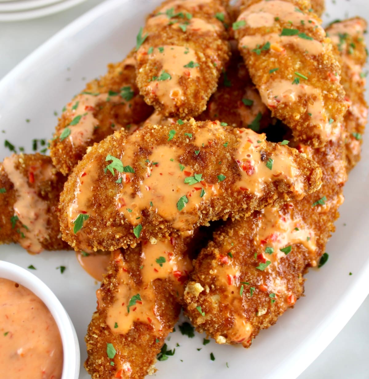 overhead view of Bang Bang Chicken Tenders on white plate with chopped parsley