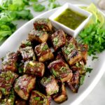 Chimichurri Steak Bites on white oval plate with sauce on side