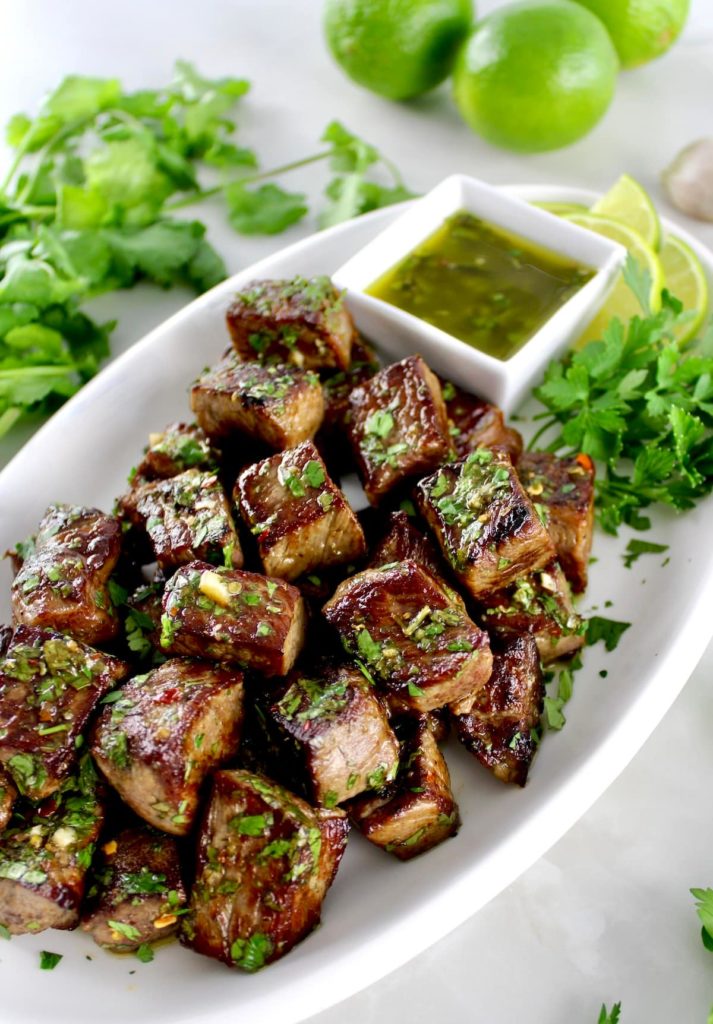 Chimichurri Steak Bites on white oval plate with sauce on side