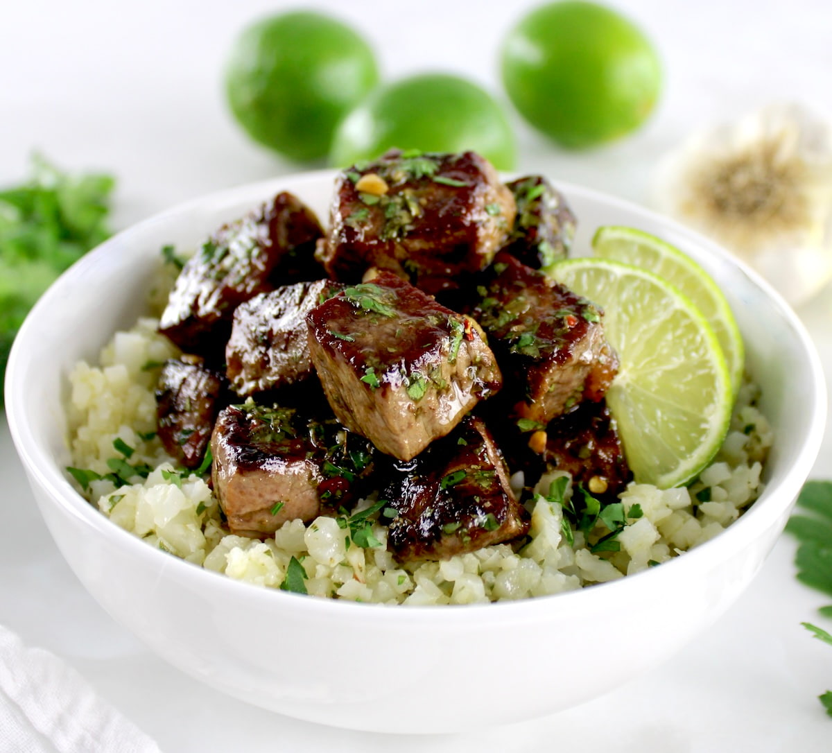 closeup of Chimichurri Steak Bites over cauliflower rice in white bowl