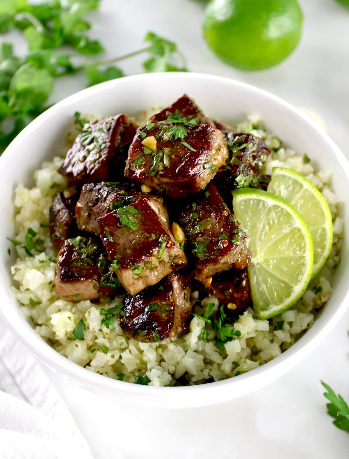 closeup of Chimichurri Steak Bites over cauliflower rice in white bowl