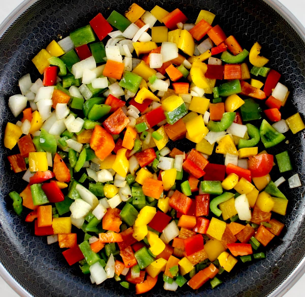 chopped red, yellow, orange and green bell peppers and onions in skillet