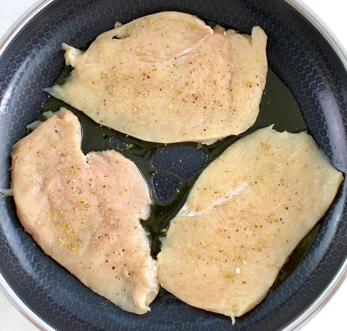 3 raw chicken breasts in skillet