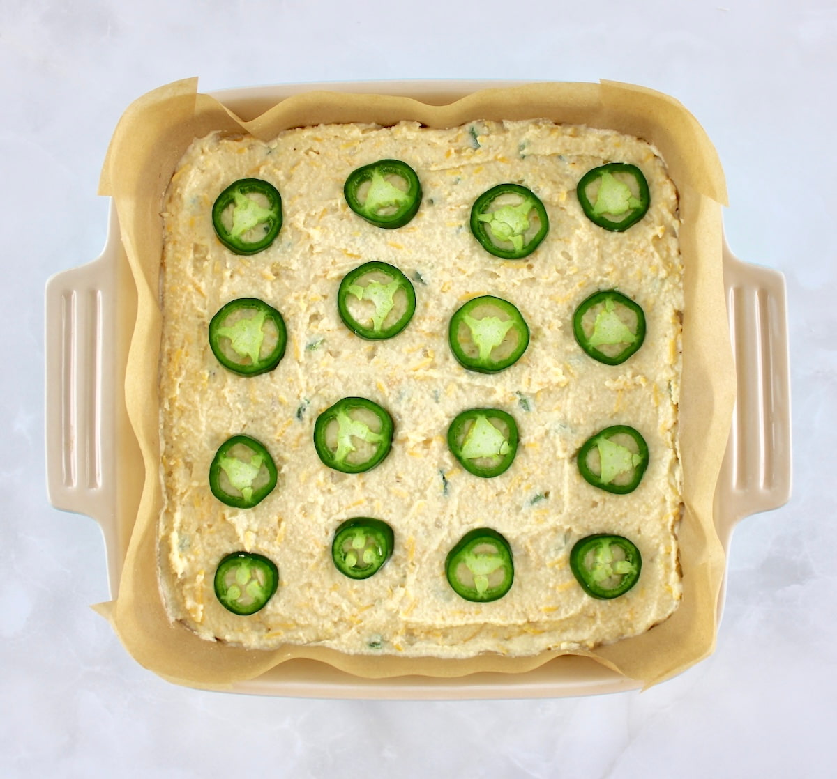 Keto Cheddar Jalapeño Cornbread batter with 12 jalapeño pepper rings on top unbaked