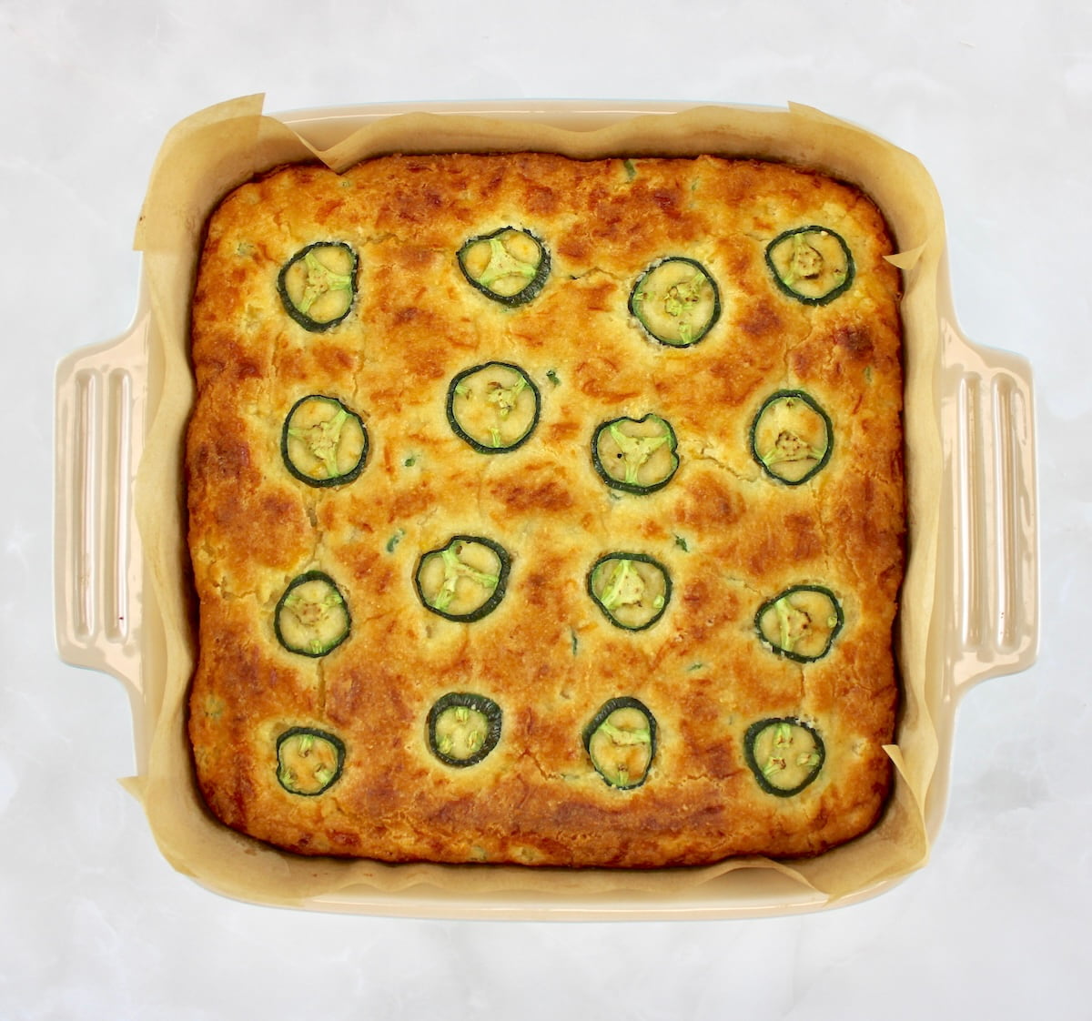 Keto Cheddar Jalapeño Cornbread in parchment lined baking dish