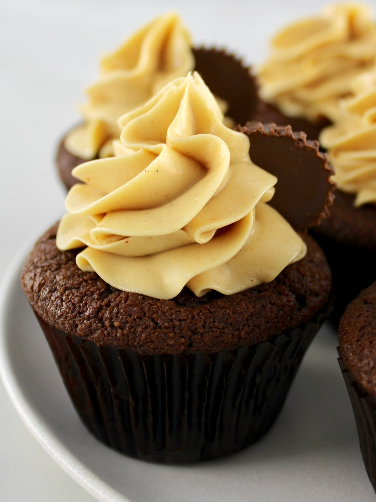 closeup of Keto Chocolate Cupcakes with Peanut Butter Frosting on white plate