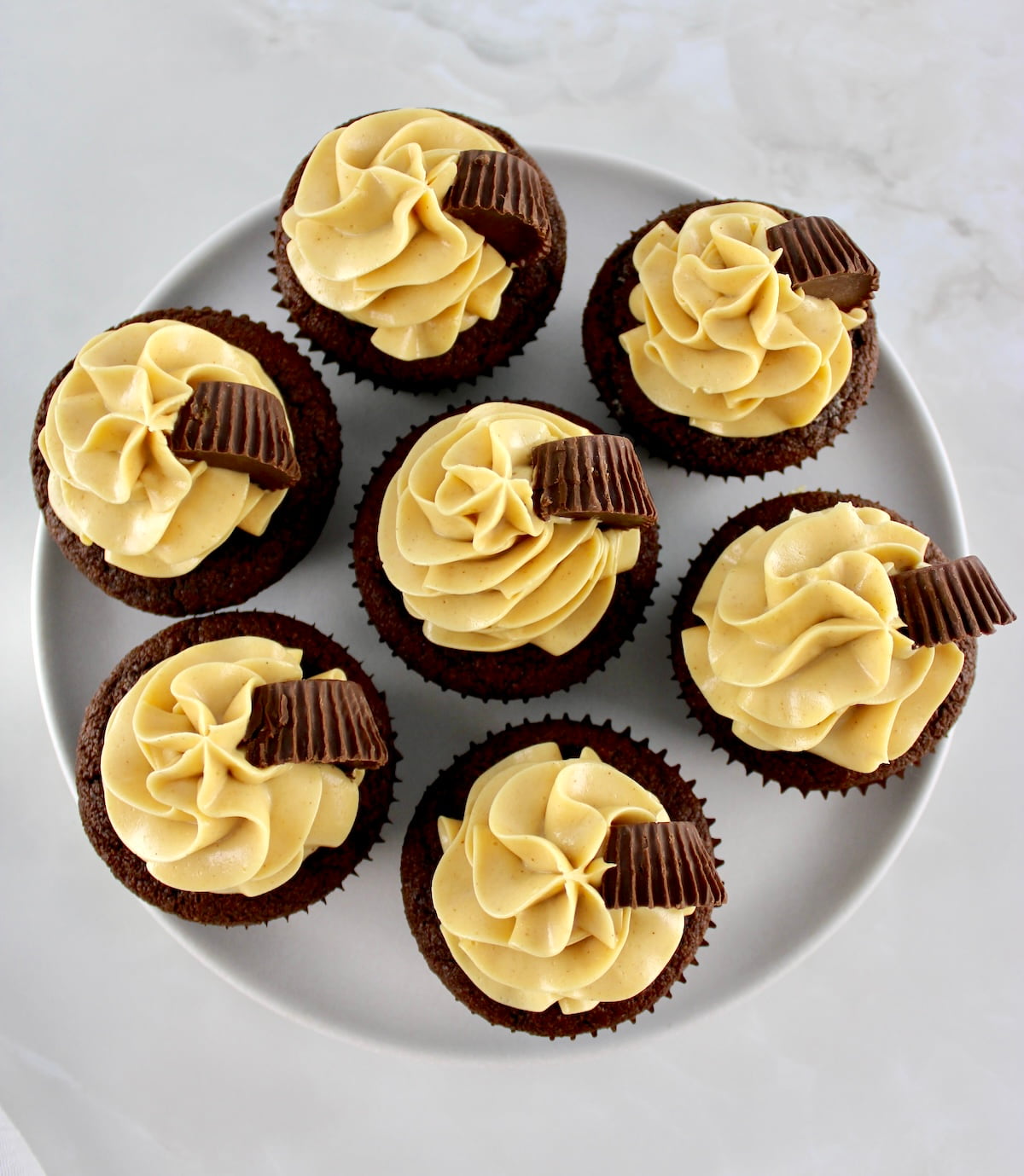 overhead view of 7 Keto Chocolate Cupcakes with Peanut Butter Frosting on white cake stand
