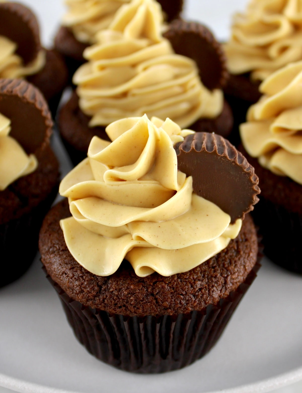 closeup overhead view of Keto Chocolate Cupcakes with Peanut Butter Frosting on white cake stand