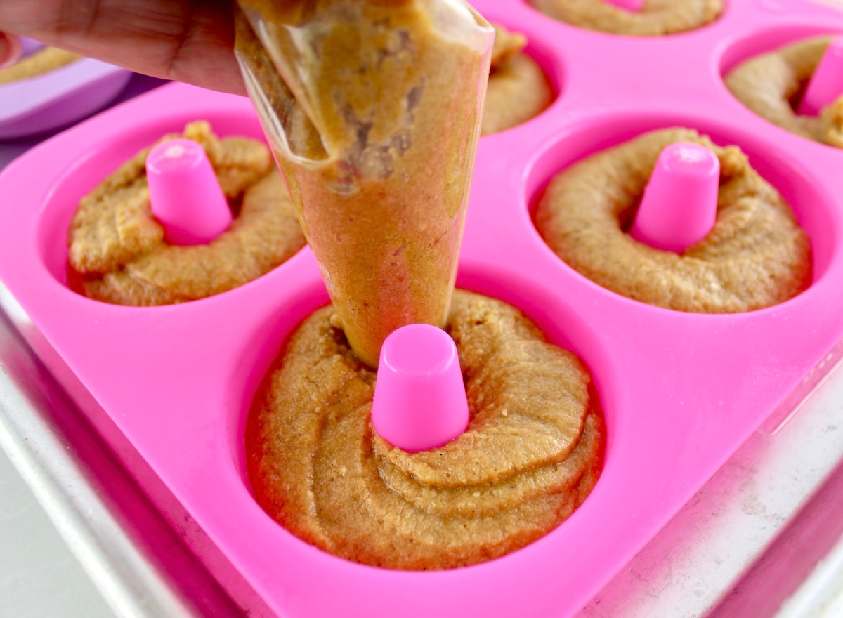 Keto Pumpkin Donuts batter being piped into pink donut mold