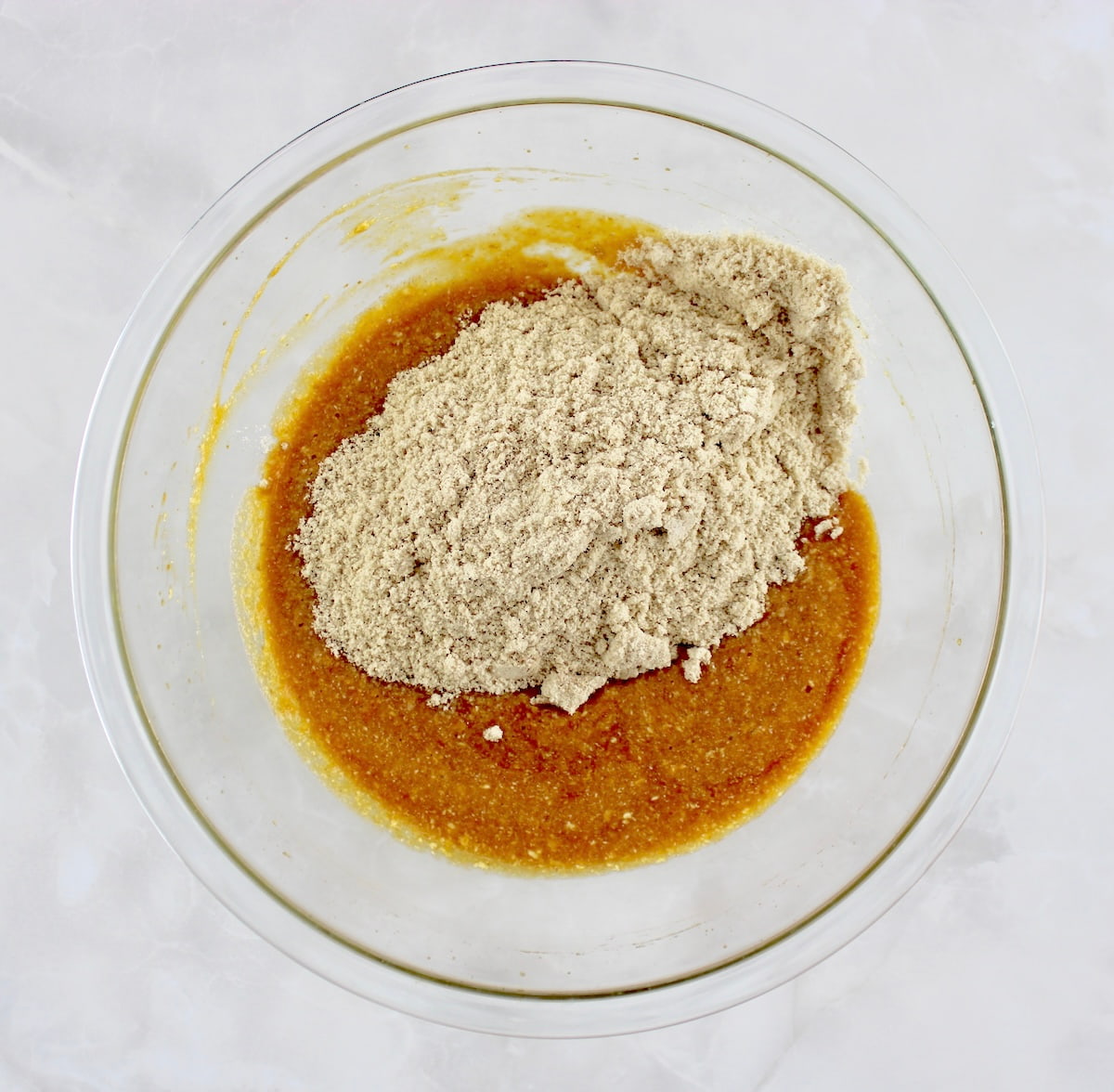 Keto Pumpkin Donuts wet ingredients with dry ingredients on top in glass bowl