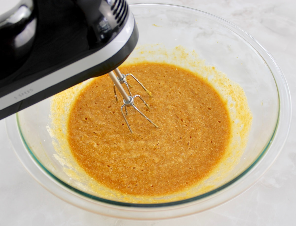 wet ingredients for Keto Pumpkin Donuts being mixing in glass bowl with hand mixer