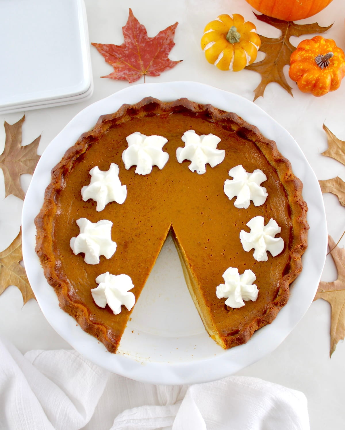 overhead view of Keto Pumpkin Pie with slice missing and whip cream on top