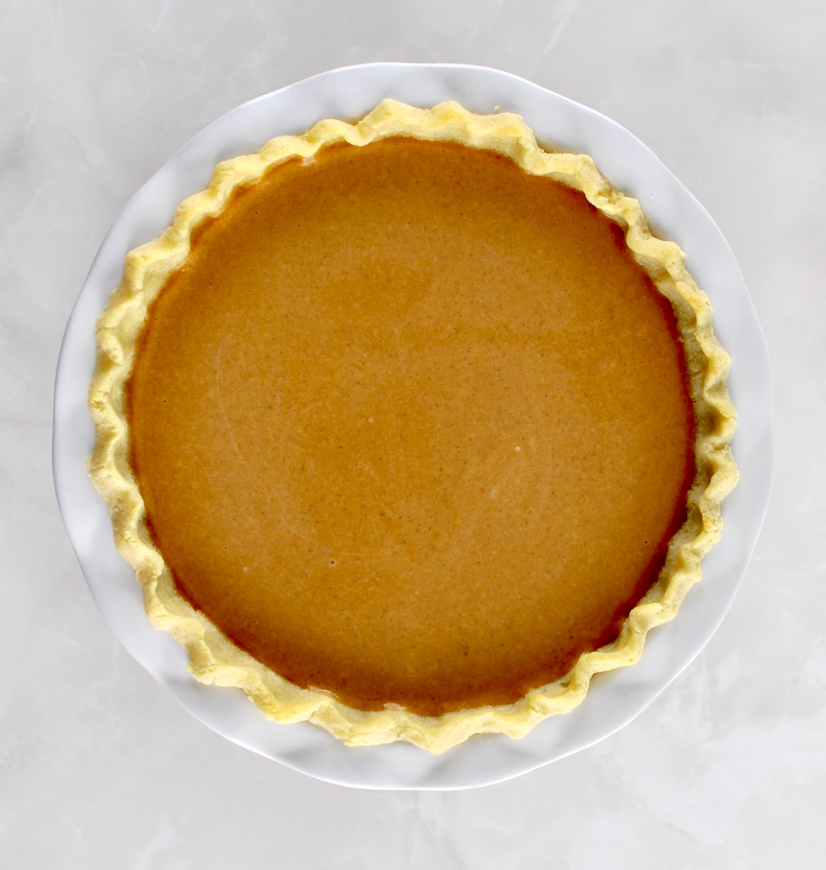 Keto Pumpkin Pie in white pie dish unbaked
