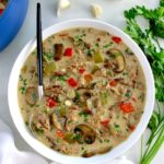 overhead view of Philly Cheesesteak Soup in white bowl with spoon on side