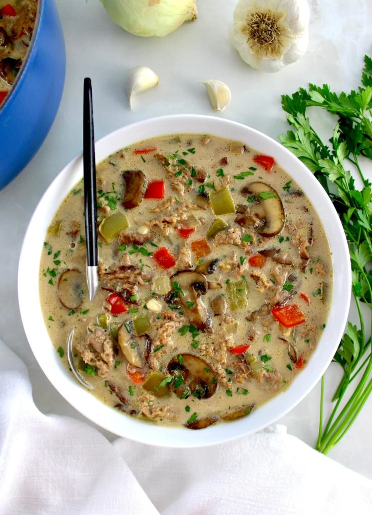 overhead view of Philly Cheesesteak Soup in white bowl with spoon on side