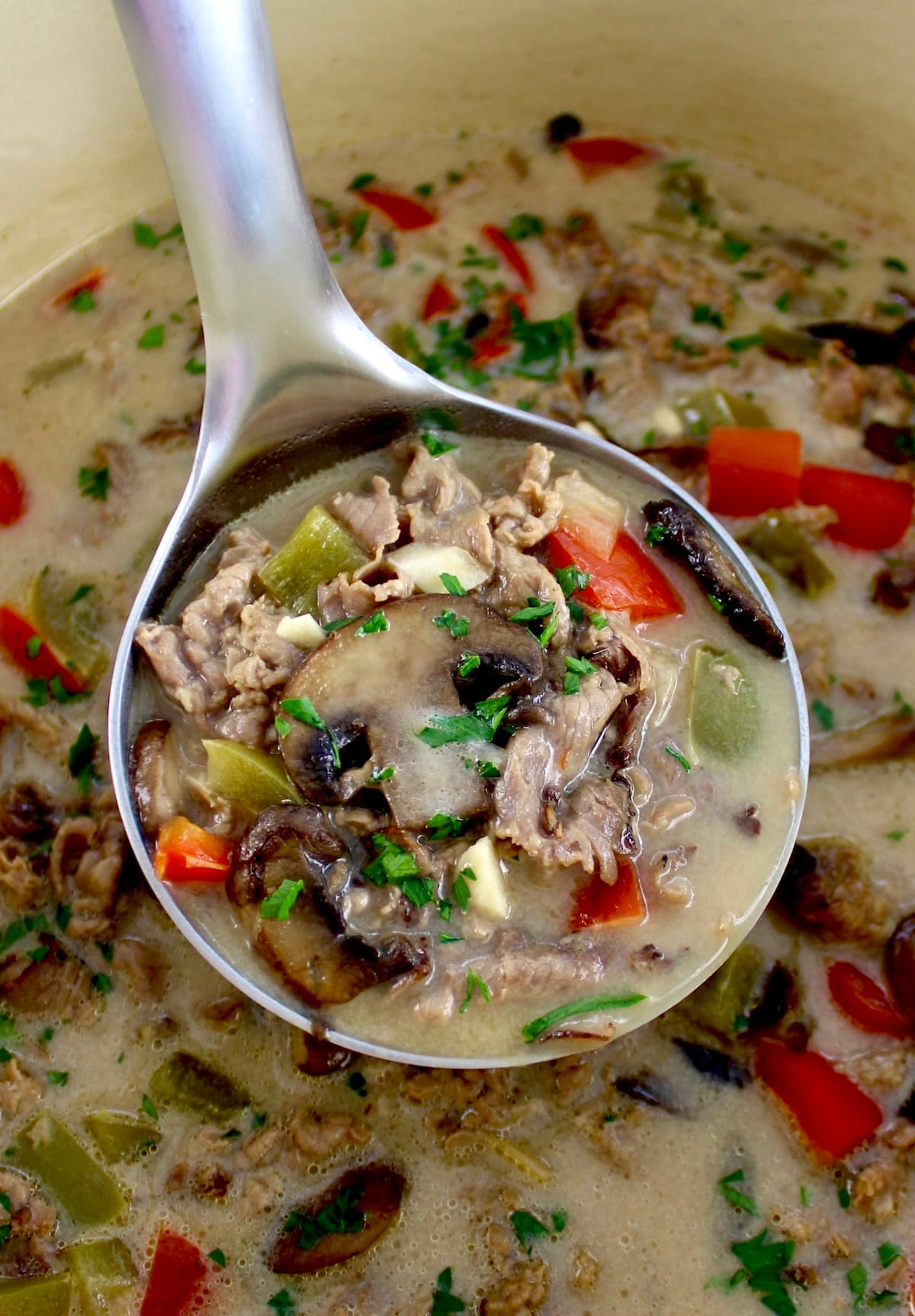 Philly Cheesesteak Soup in Dutch oven with ladle full