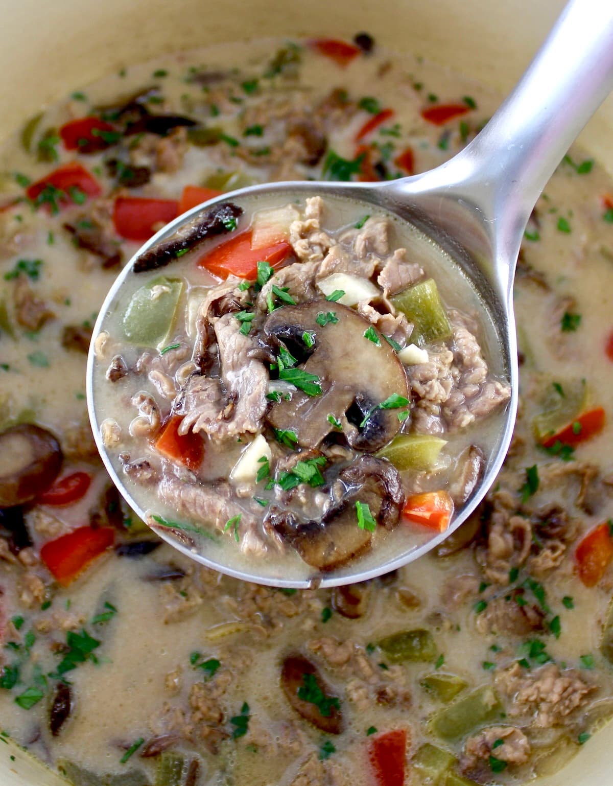 Philly Cheesesteak Soup in ladle over dutch oven