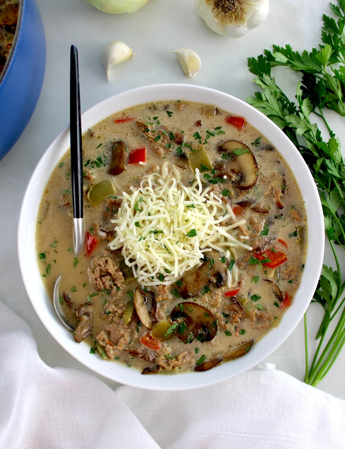 overhead view of Philly Cheesesteak Soup with shredded cheese on top
