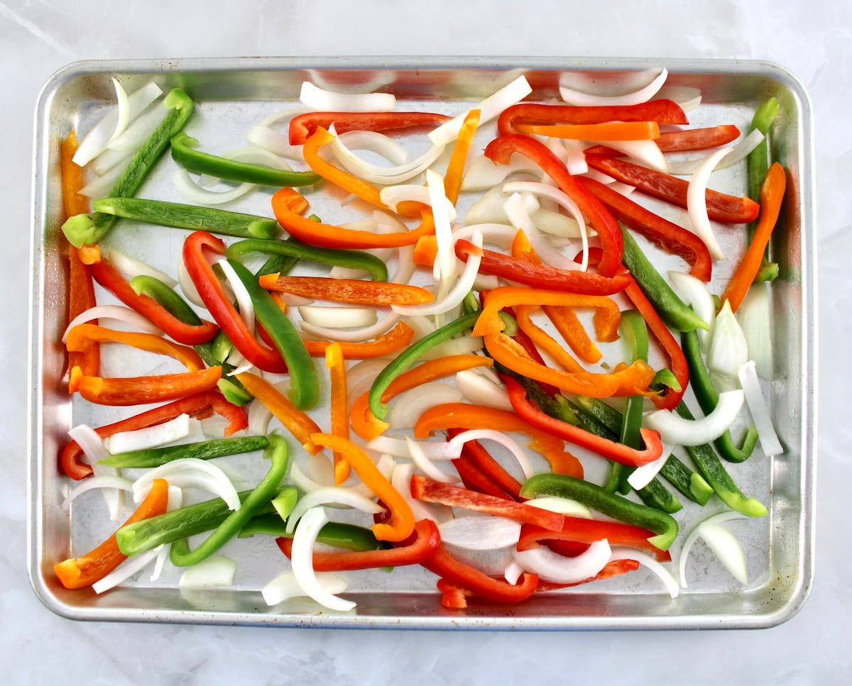 sliced bell peppers and onions on baking sheet