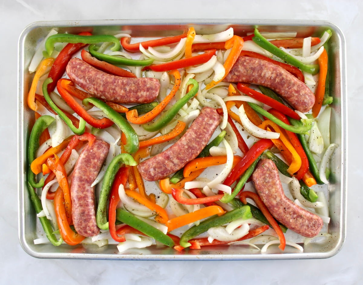 5 sausage links, sliced bell peppers and onions with salt, pepper and olive oil on baking sheet