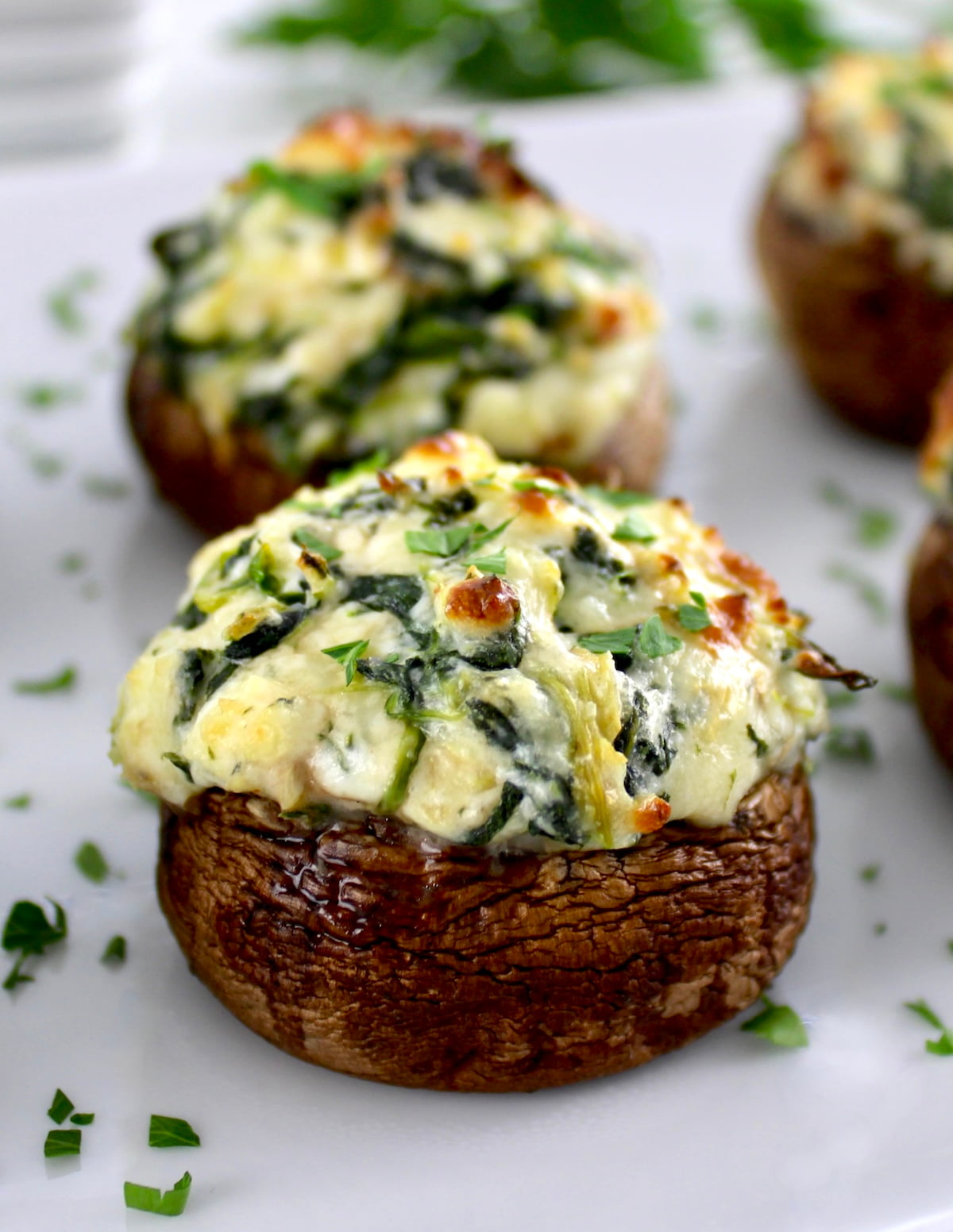 closeup of Spinach Artichoke Stuffed Mushrooms on white plate