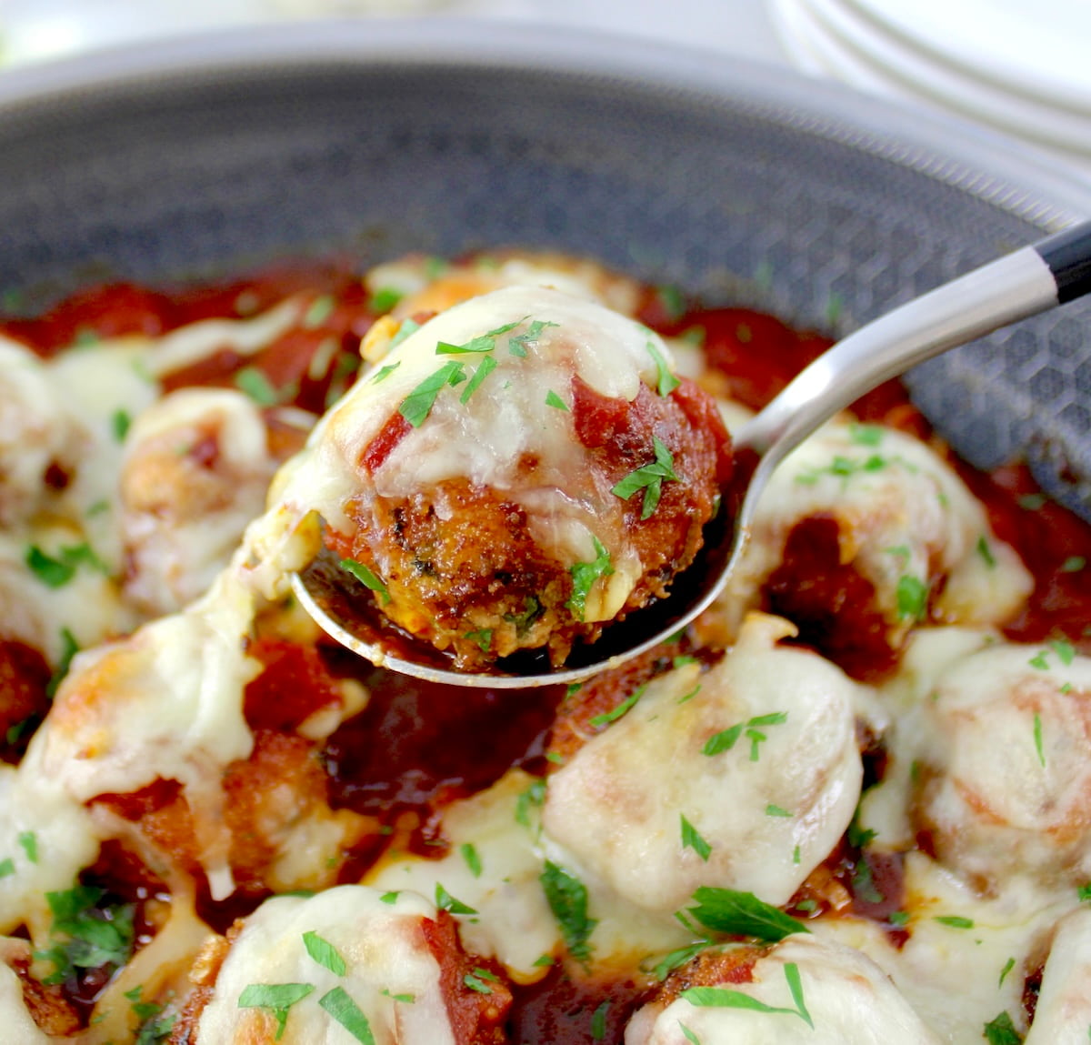 lifting up Chicken Parmesan Meatball out of skillet
