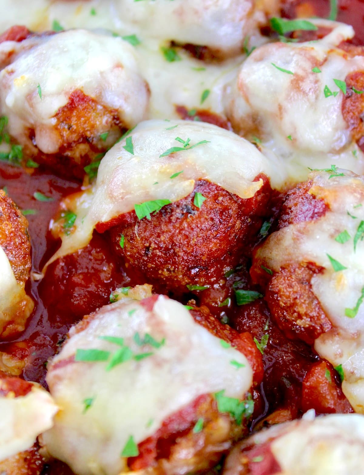 closeup of Chicken Parmesan Meatballs in skillet with melted mozzarella on top
