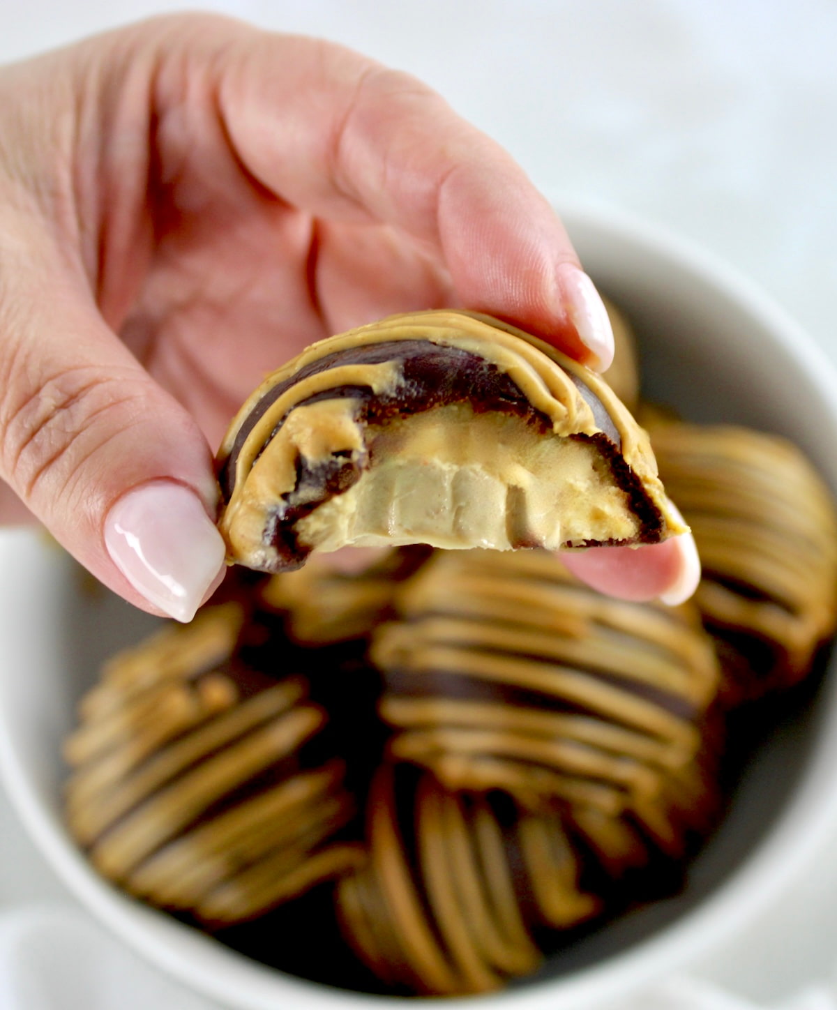 holding up Chocolate Peanut Butter Truffle with bite missing