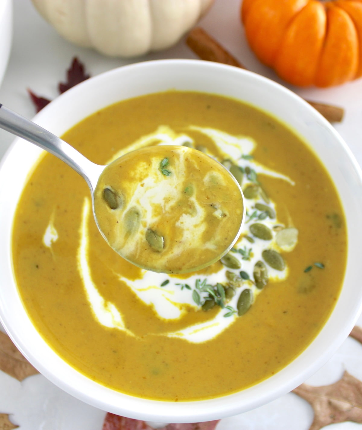 Easy Pumpkin Soup in white bowl with spoon holding up some