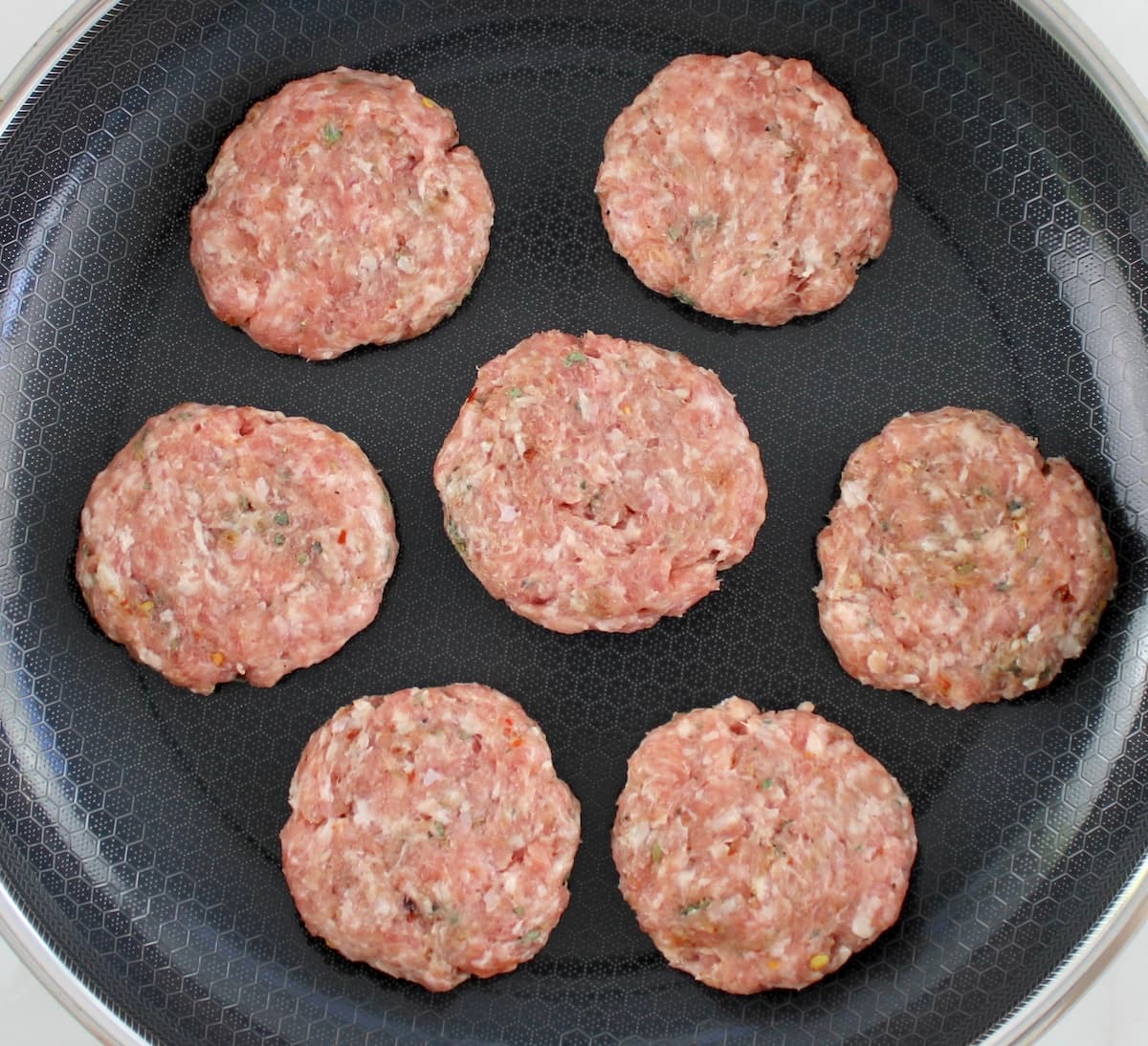 7 raw Homemade Breakfast Sausage cooking in skillet