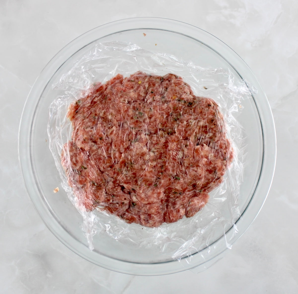 Homemade Breakfast Sausage pork in glass bowl covered in plastic wrap
