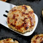 Homemade Breakfast Sausage held up on silver spatula over frying pan