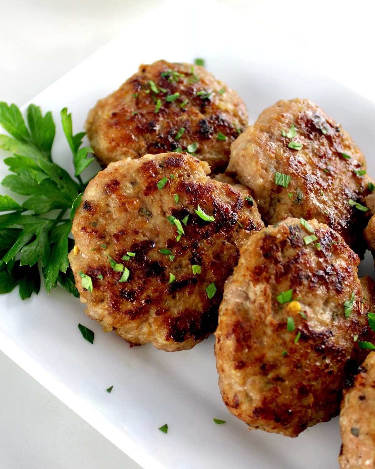 Homemade Breakfast Sausage patties on white plate with parsley