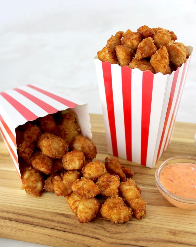 Keto Popcorn Chicken in 2 popcorn containers, one spilled over onto cutting board