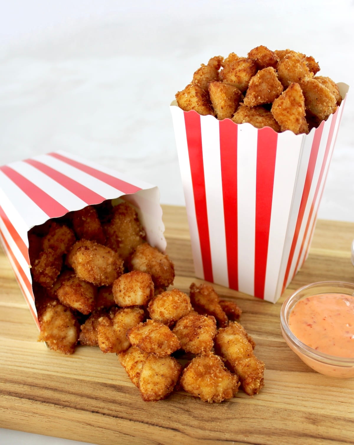Keto Popcorn Chicken in 2 popcorn containers, one spilled over onto cutting board