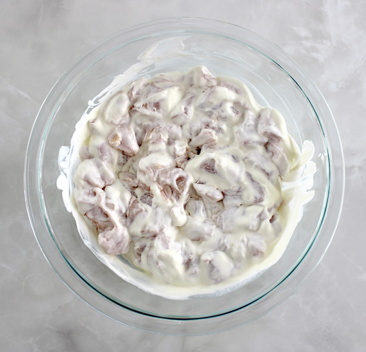 chicken pieces in buttermilk in glass bowl