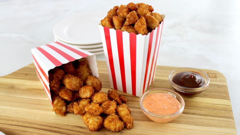 Keto Popcorn Chicken in 2 popcorn containers, one spilled over onto cutting board
