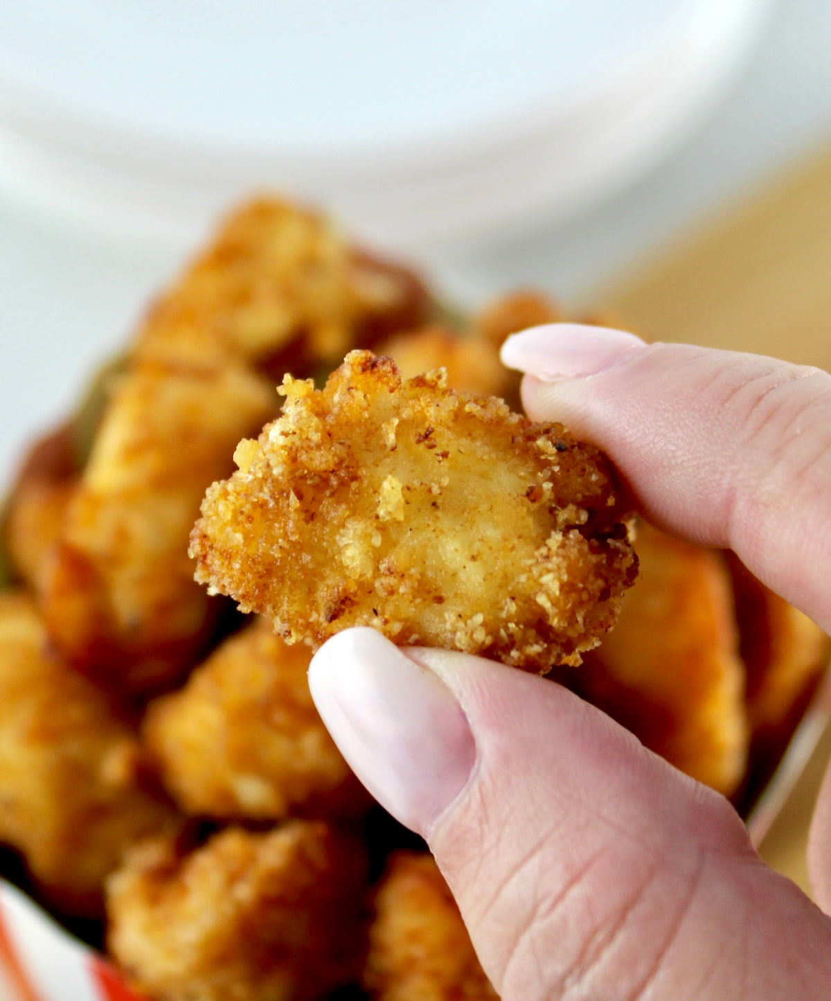 holding up piece of Keto Popcorn Chicken